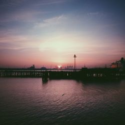 Silhouette of bridge over river against sky