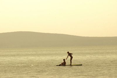 Silhouette man standing in sea against clear sky