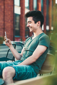 Side view of young man using mobile phone