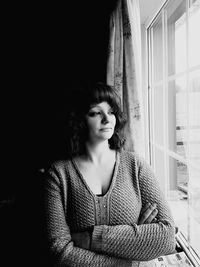 Thoughtful woman looking through window at home