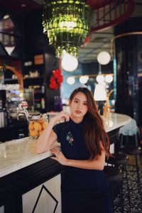 Portrait of young woman standing in restaurant