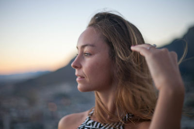 Portrait of beautiful young woman against sky during sunset