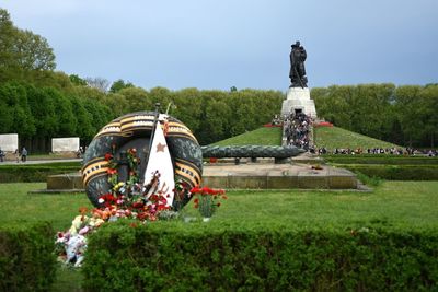 Bouquets by statues at soviet war memorial against clear sky