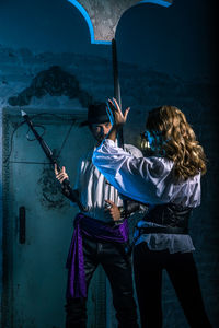 Man looking at woman holding sword while standing in abandoned building