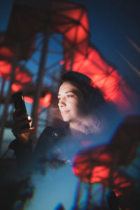 Reflection of woman using phone on window at night