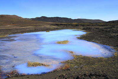 Scenic view of land and mountains against blue sky