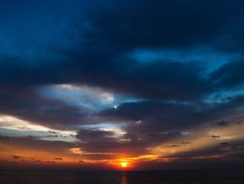 Scenic view of sea against dramatic sky during sunset