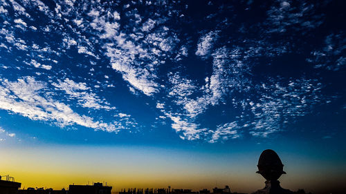 Low angle view of silhouette trees against blue sky