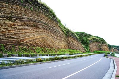 Empty road by rock formation