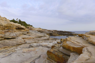 Rock formation on beach against sky