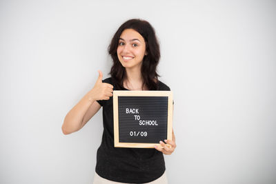 Young woman using digital tablet while standing against white background