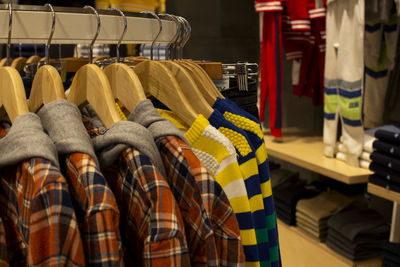 Shirts and pants hanging on hangers on a clothing rack and arranged in a shelf in a clothing store