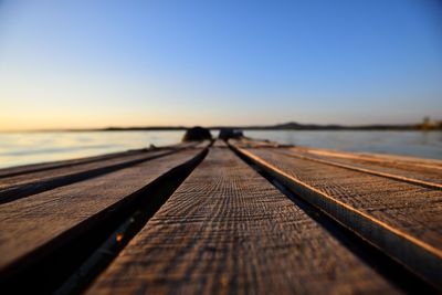 Surface level view of pier on sea against clear sky