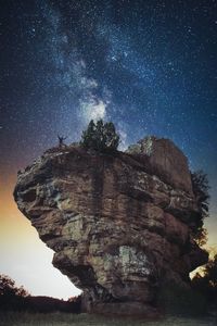 Low angle scenic view of star field over rock formation against sky at night