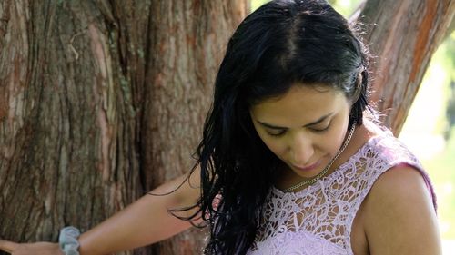 Young woman looking at tree trunk