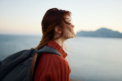 Portrait of a smiling young woman standing against sea