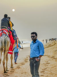 Young man riding horse standing on sand