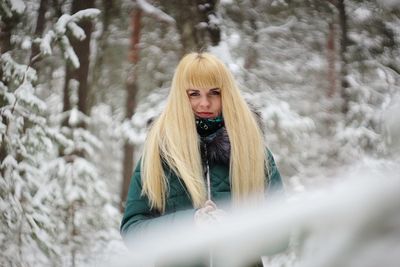 Portrait of young woman standing in forest during winter