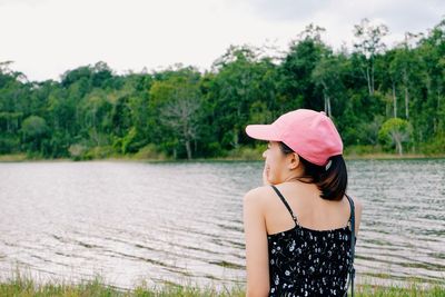 Woman standing by pink lake against trees