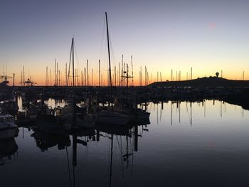 Silhouette of sailboats at harbor during sunset