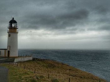 Lighthouse by sea against sky