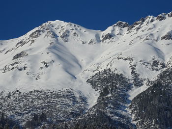 Scenic view of snowcapped mountains against clear blue sky