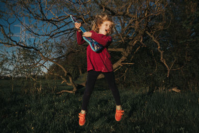 Girl playing with small guitar on field