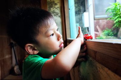 Cute boy playing with toy car on window sill at home