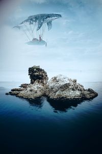 Rock formation in sea against sky