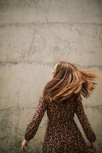 Carefree woman tossing hair against wall