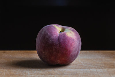 A peach on a kitchen wooden board