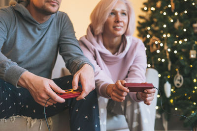 Crop photo of young family in home clothes playing video games on couch on background 