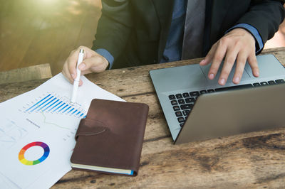 Midsection of man using mobile phone on table