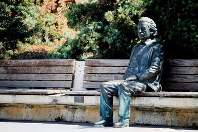 Statue of man sitting on bench in park