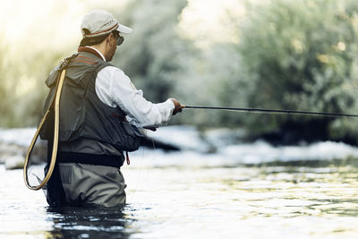 Rear view of man fishing in river