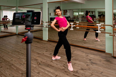 Full length of woman with arms raised on floor