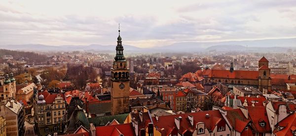 Aerial view of city buildings against cloudy sky