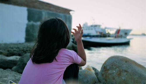 Rear view of young woman on rock at sea