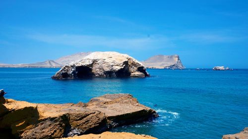 Scenic view of rocks in sea against blue sky