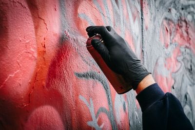 Close-up of persons hand tagging wall with graffiti