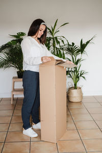 Young woman looking away while standing on potted plant