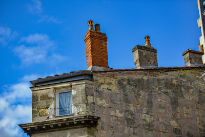 Low angle view of bird perching on building against sky