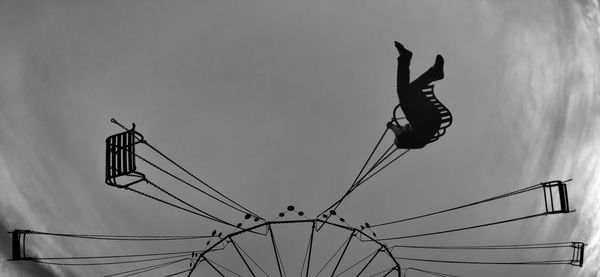 Low angle view of woman jumping against sky
