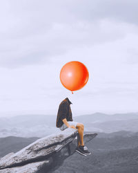 Low angle view of man with balloons against sky