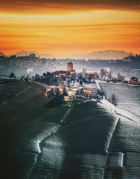 Aerial view of snow covered landscape against sky during sunset