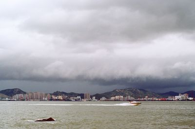 Boats in sea against cloudy sky