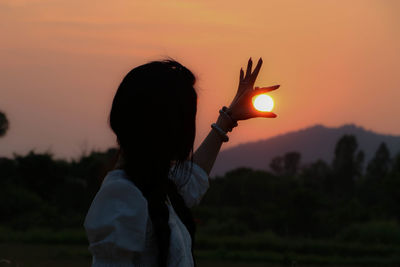 Rear view of silhouette man standing against sky during sunset