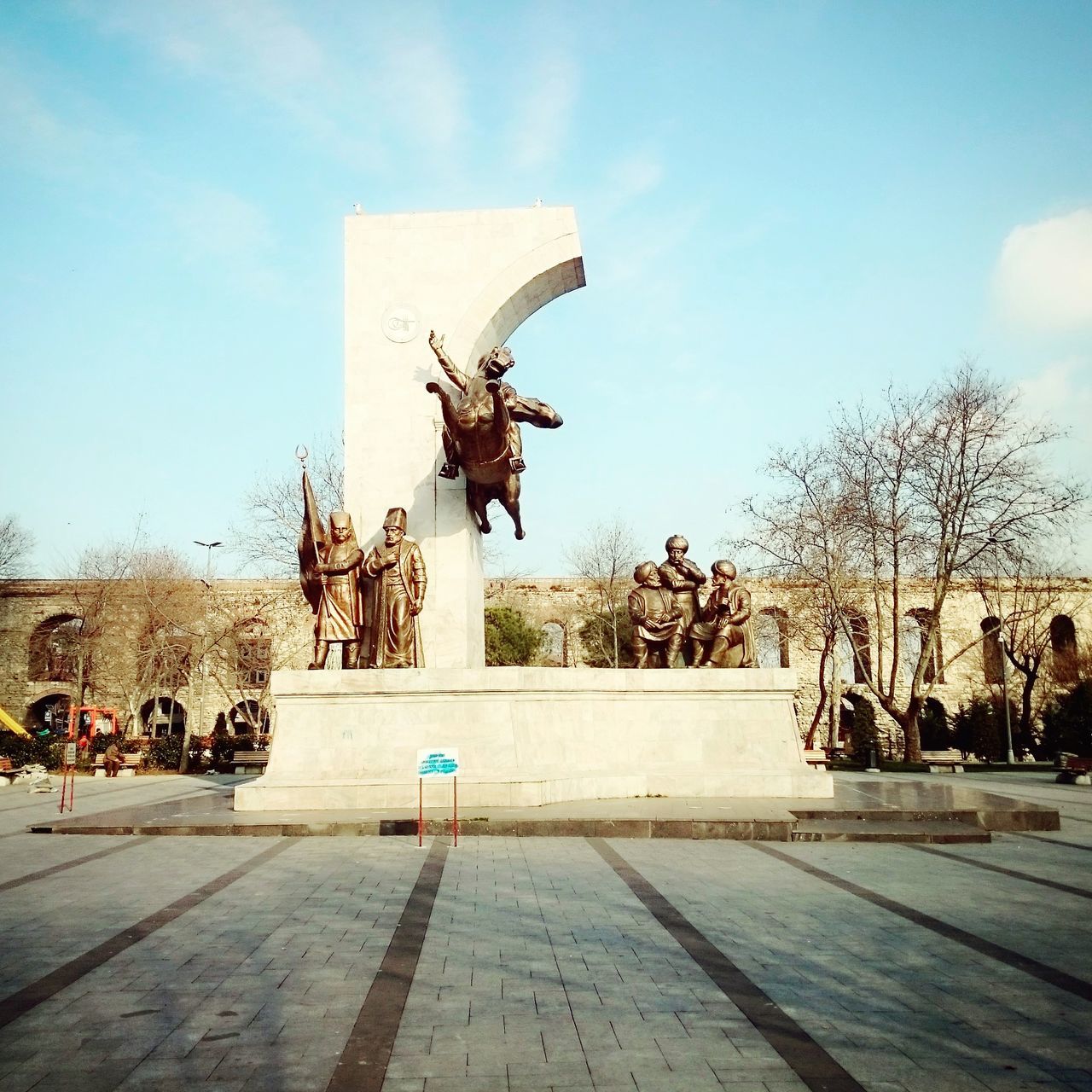 tree, built structure, building exterior, architecture, art and craft, sky, sculpture, art, statue, animal representation, human representation, creativity, blue, clear sky, day, sunlight, outdoors, incidental people, shadow