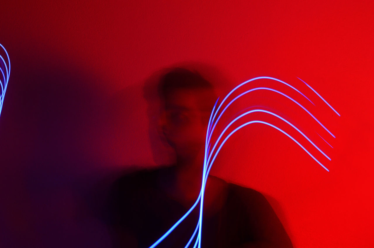 red, one person, indoors, close-up, long exposure, motion, real people, illuminated, studio shot, blurred motion, colored background, blue, light painting, wall - building feature, communication, lifestyles, glowing, red background, smoke - physical structure