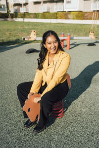 Happy woman sitting on spring horse at playground